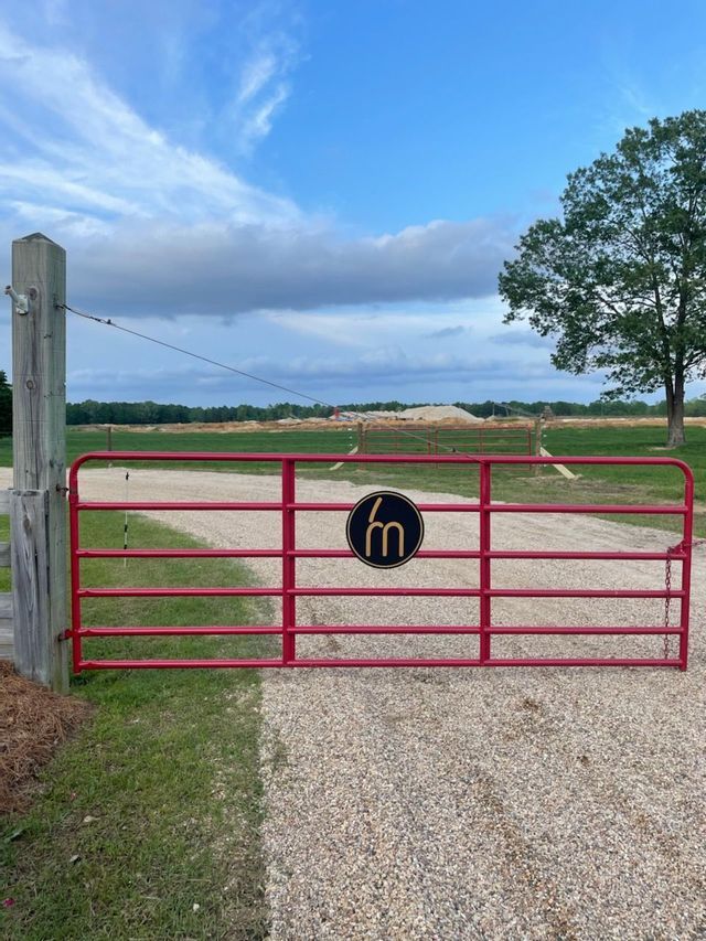 A red metal farm gate with a circular