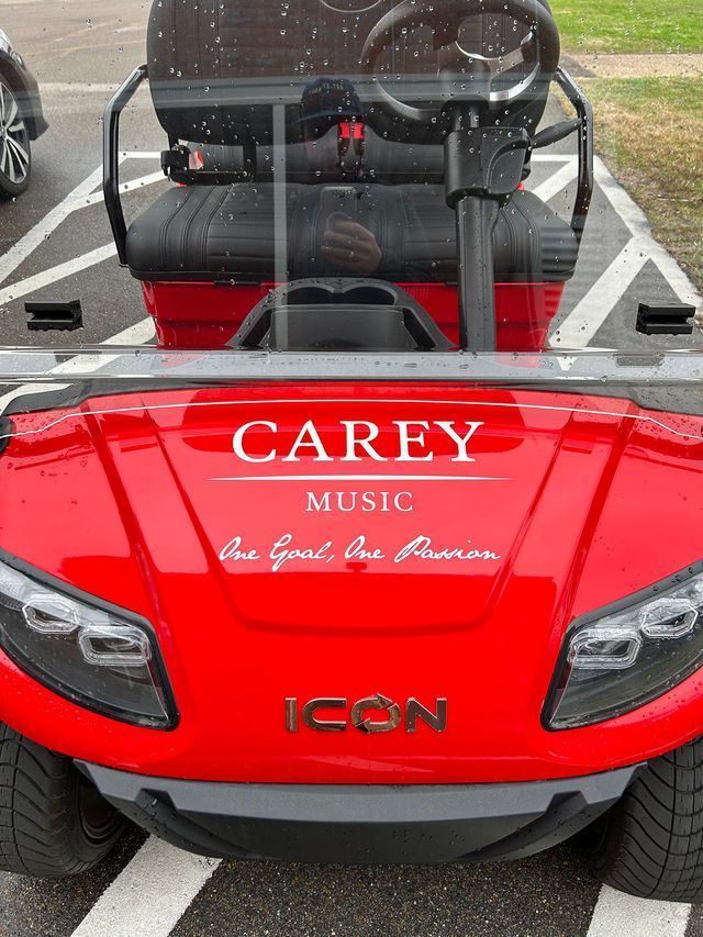 A red ICON golf cart parked in a lot, with 