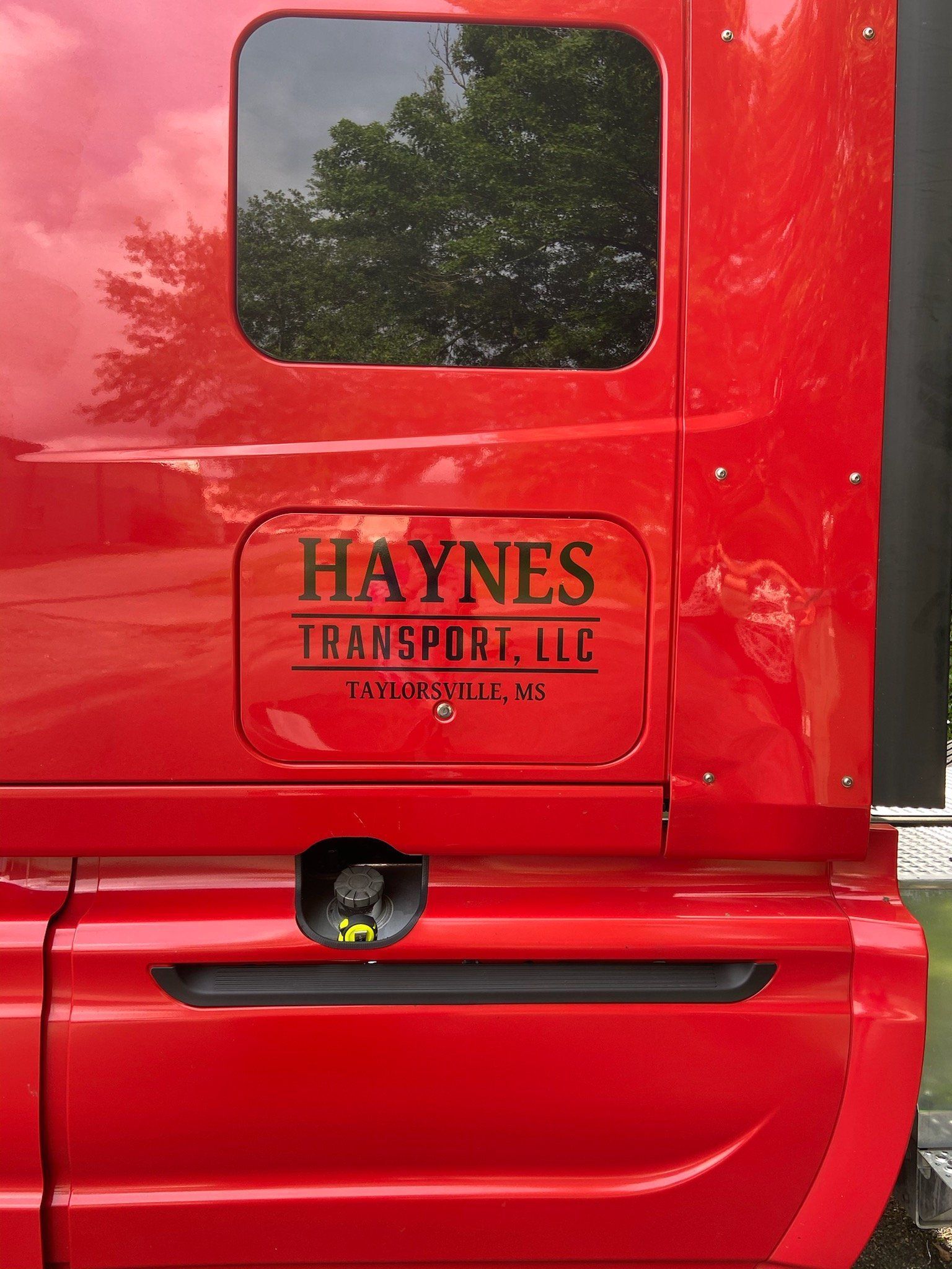 Side view of a bright red truck cab with a black decal that reads 