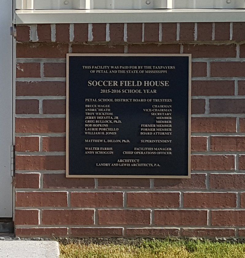 A commemorative plaque on a brick wall for the 2015-2016 Soccer Field House, listing school district board members.