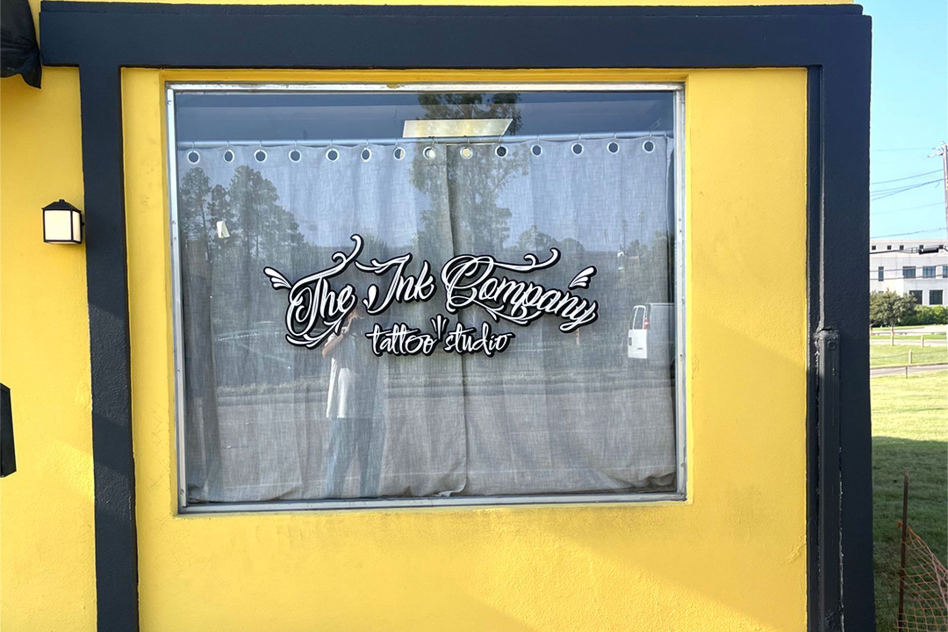 A window on a bright yellow building displays the black logo 