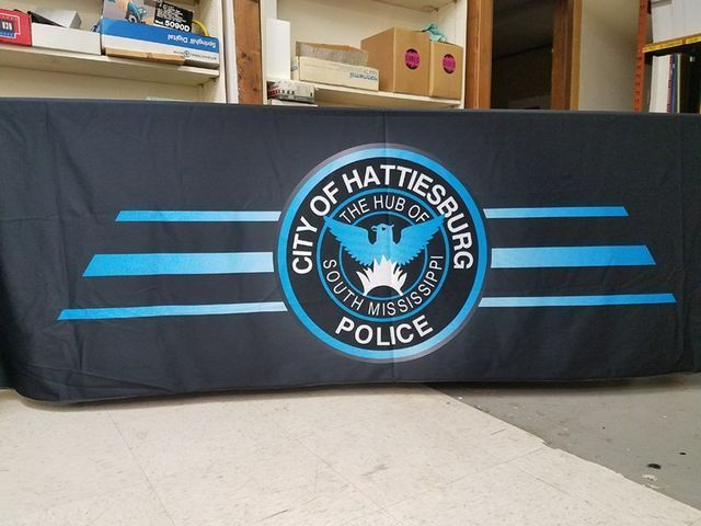 A black table cover displays the Hattiesburg Police Department seal, accented by blue horizontal stripes.