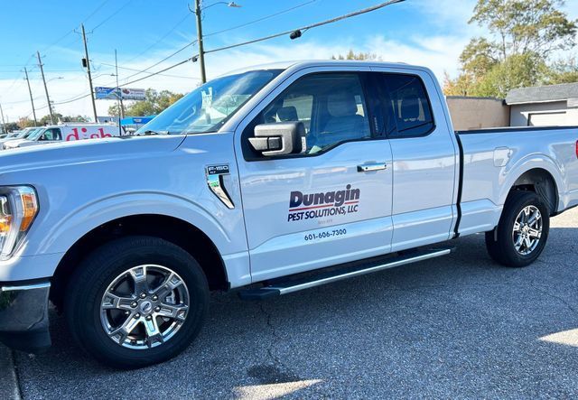 A white Dunagin HVAC Solutions Ford pickup truck parked on an asphalt lot under a sunny blue sky.