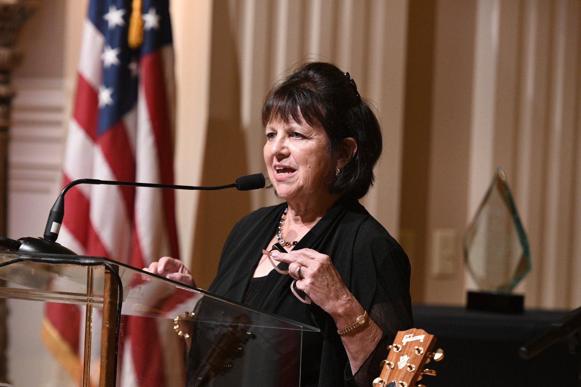 A woman is standing at a podium speaking into a microphone.