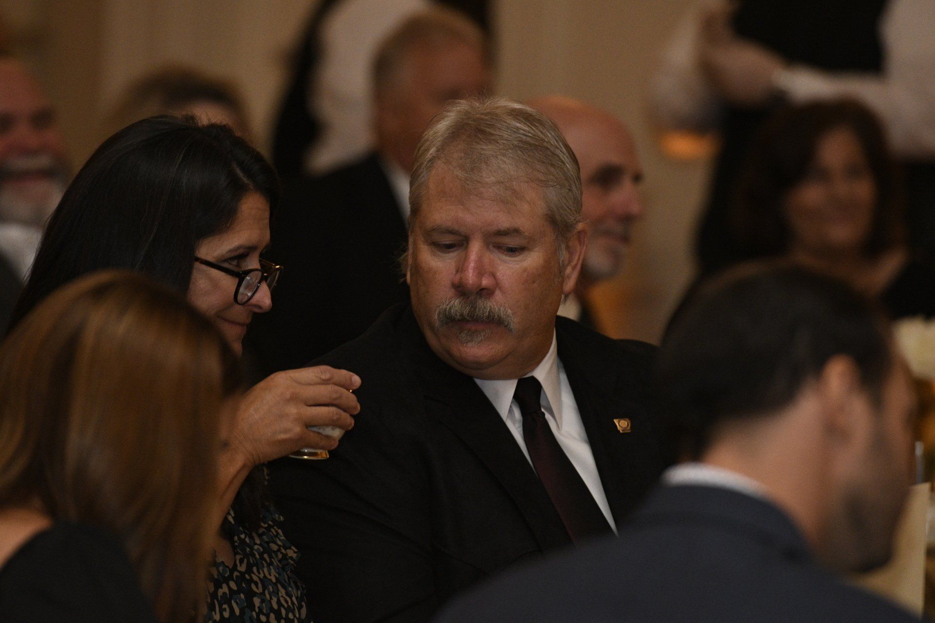 A man in a suit and tie is sitting in a crowd of people.