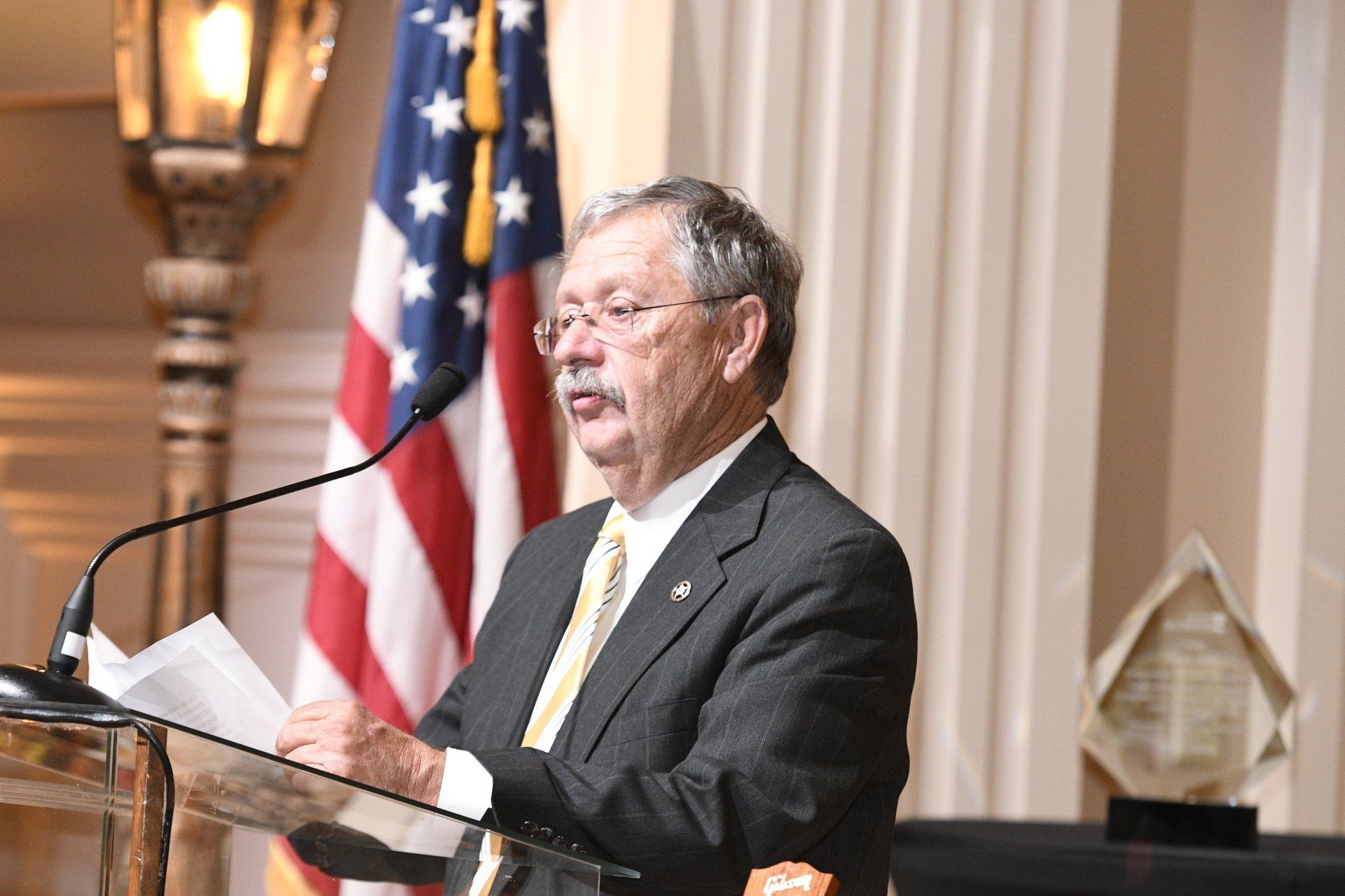 A man in a suit and tie is standing at a podium giving a speech.