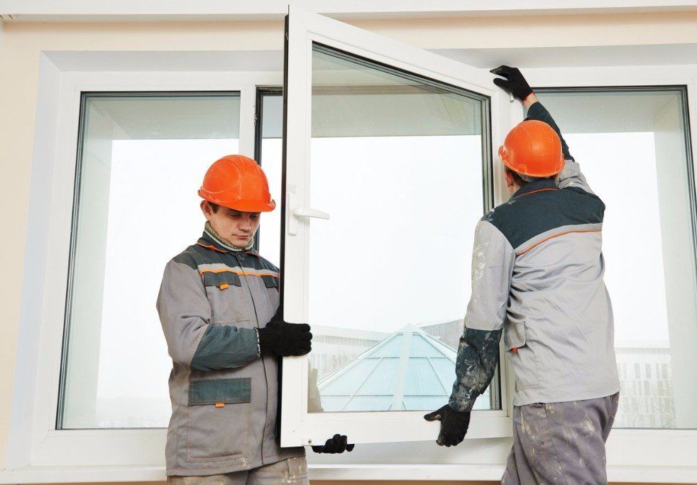 Two men in hard hats installing a window