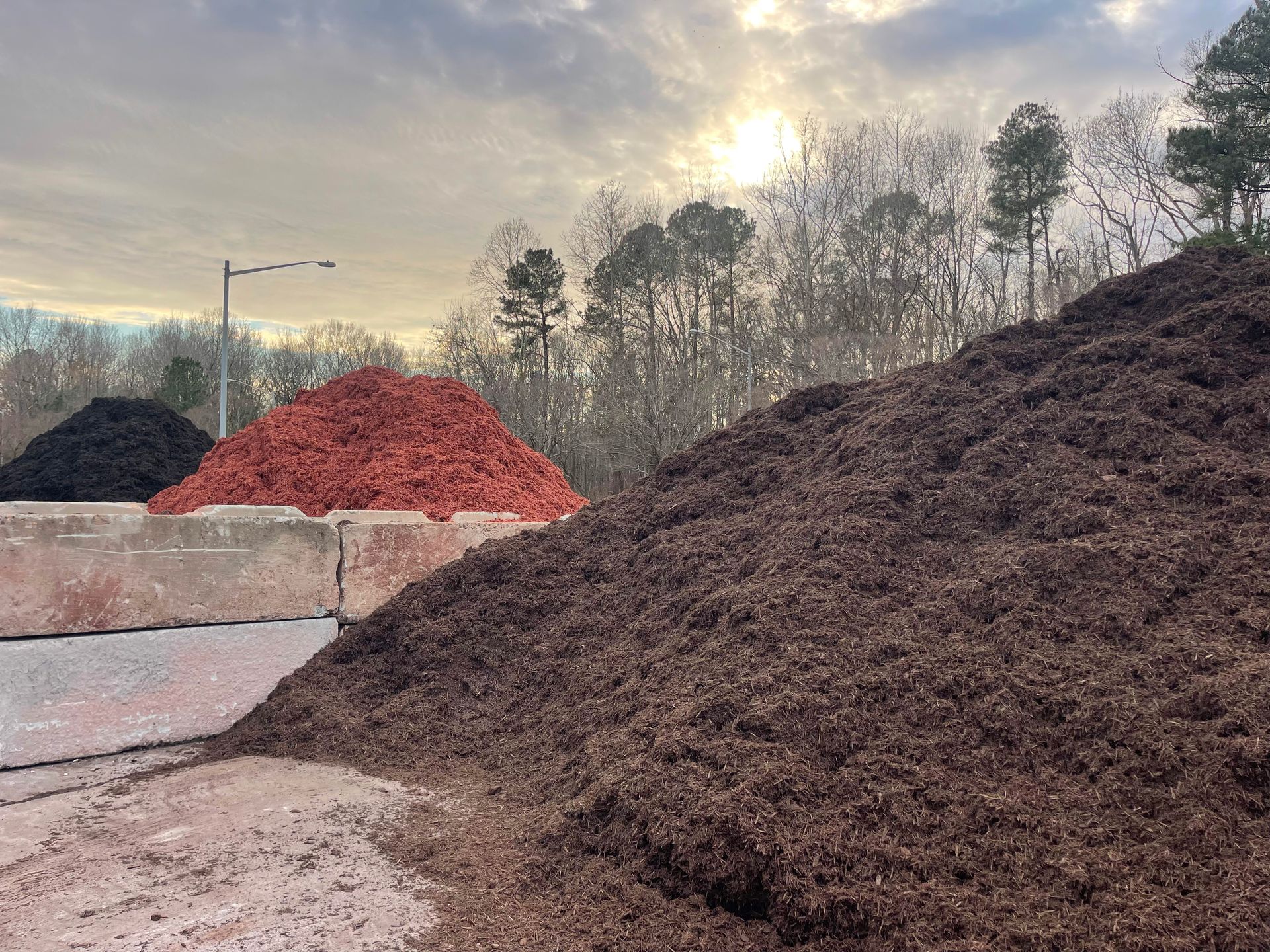 a pile of mulch is sitting next to a pile of dirt .
