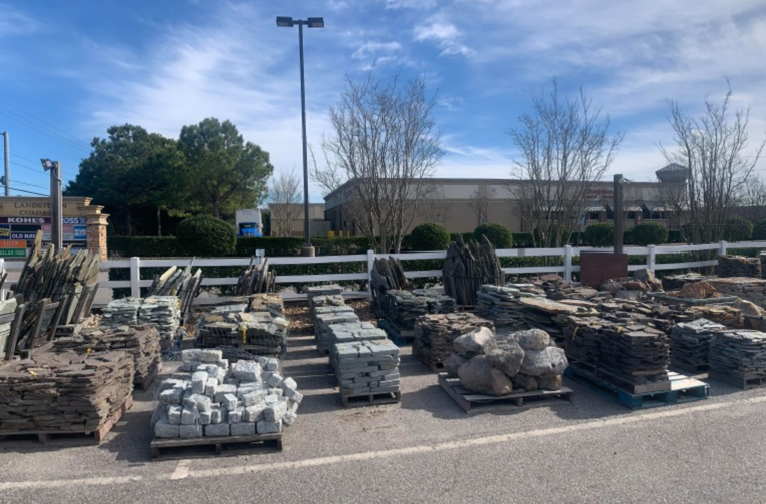 a lot of rocks are sitting on pallets in a parking lot .