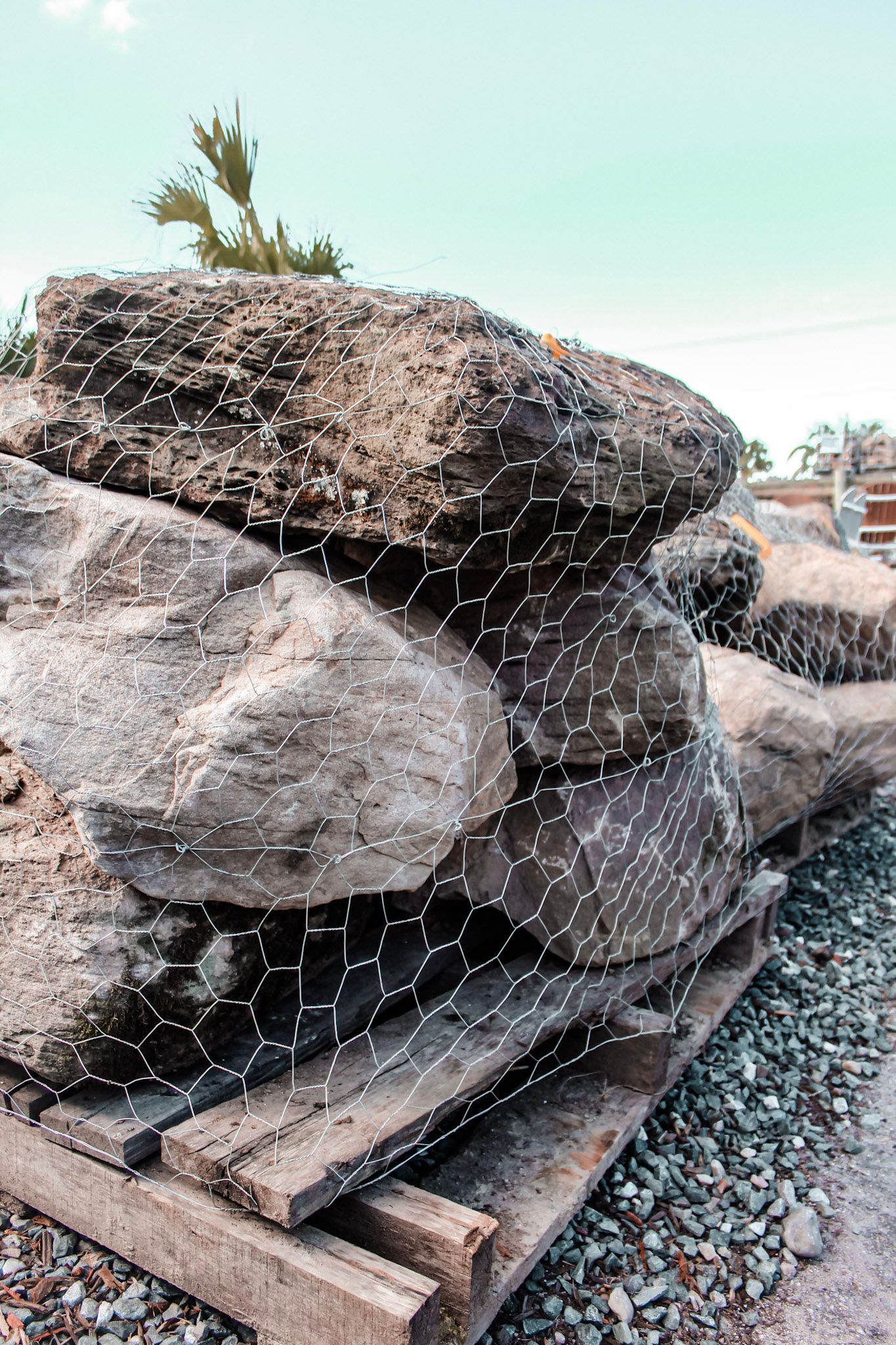 a bunch of rocks are sitting on pallets in a gravel area