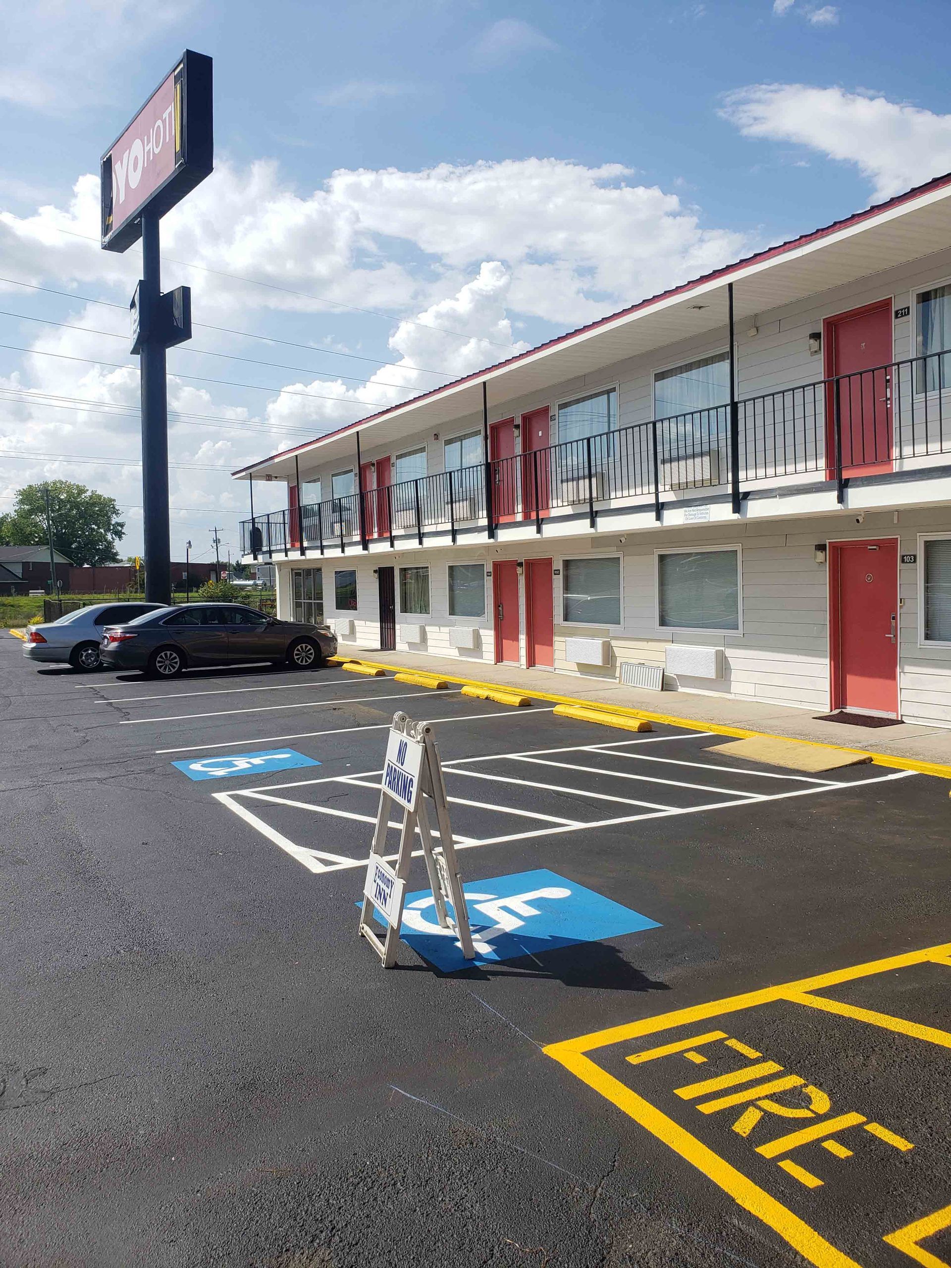 A parking lot in front of a hotel with cars parked in it.