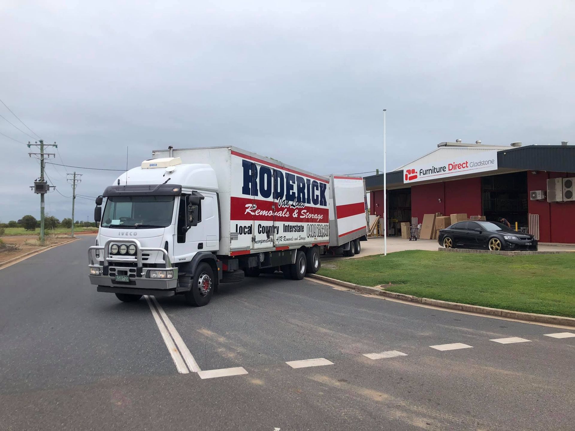 A White Truck is Parked on the Side of the Road in Front of a Building — Roderick Removals & Van Lines In Emerald, QLD