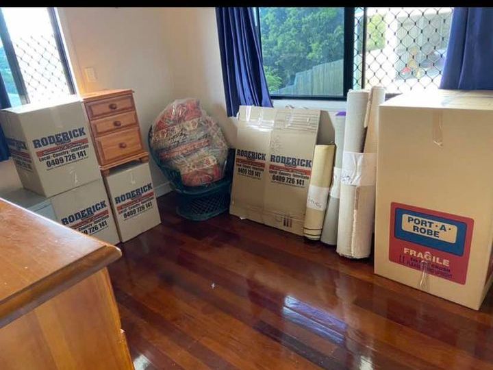 A Man is Standing in the Back of a Truck Filled With Boxes — Roderick Removals & Van Lines In Gladstone Central, QLD