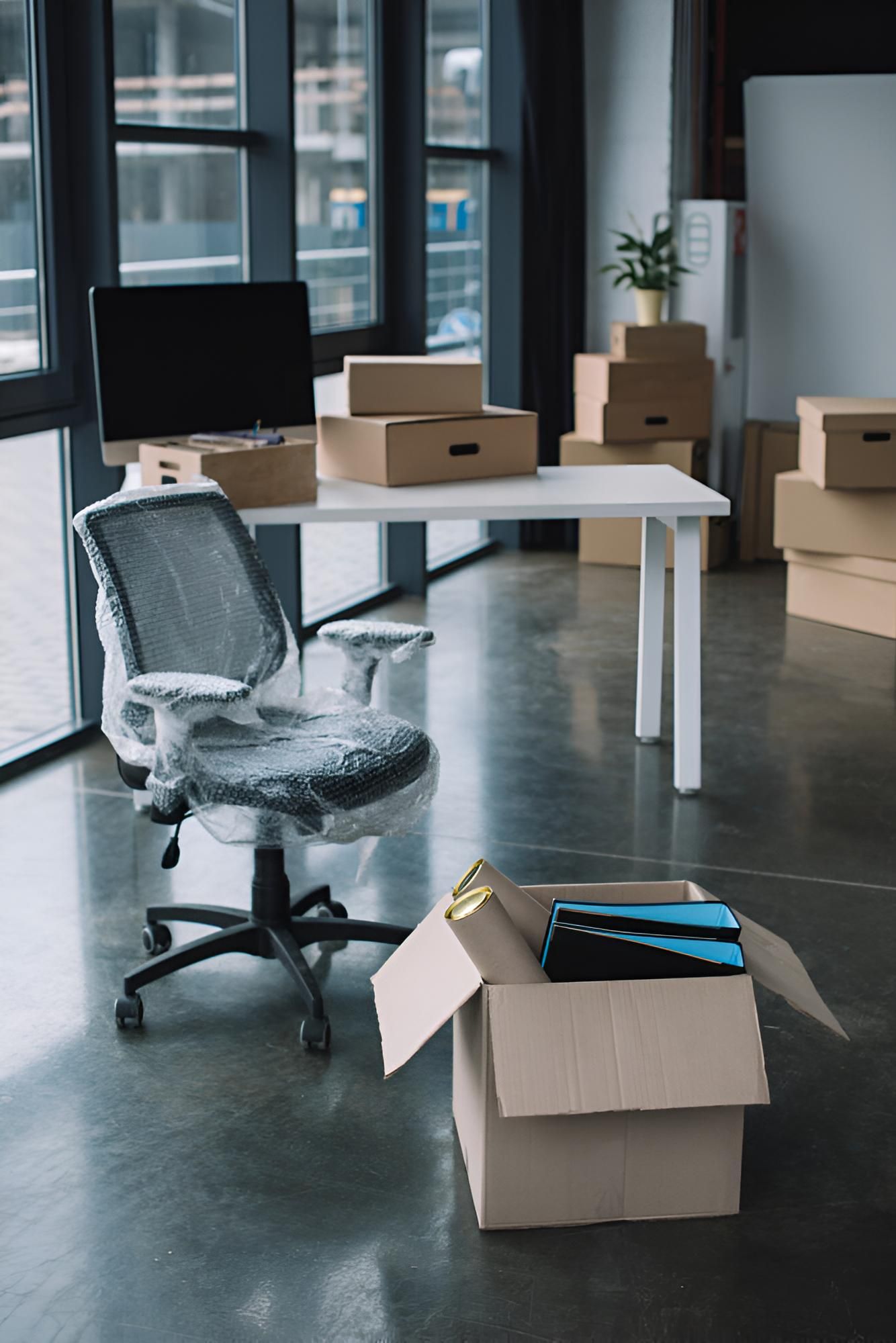 An Office With Boxes on the Floor and a Desk and Chair — Roderick Removals & Van Lines In Bowen, QLD