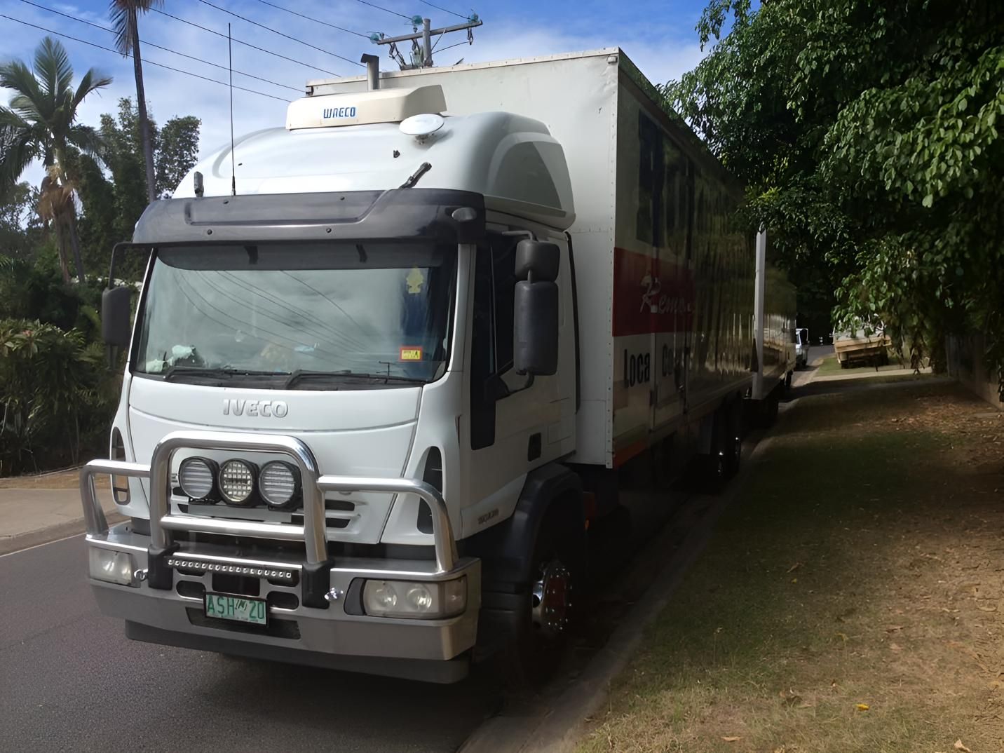 A Truck With a Blue Container on the Back is Parked in a Grassy Field — Roderick Removals & Van Lines In Gold Coast, NSW