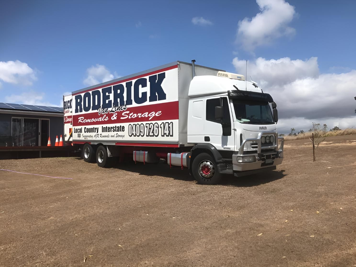 A Red and White Roderick Truck is Parked in a Dirt Field — Roderick Removals & Van Lines In Sunshine Coast, QLD