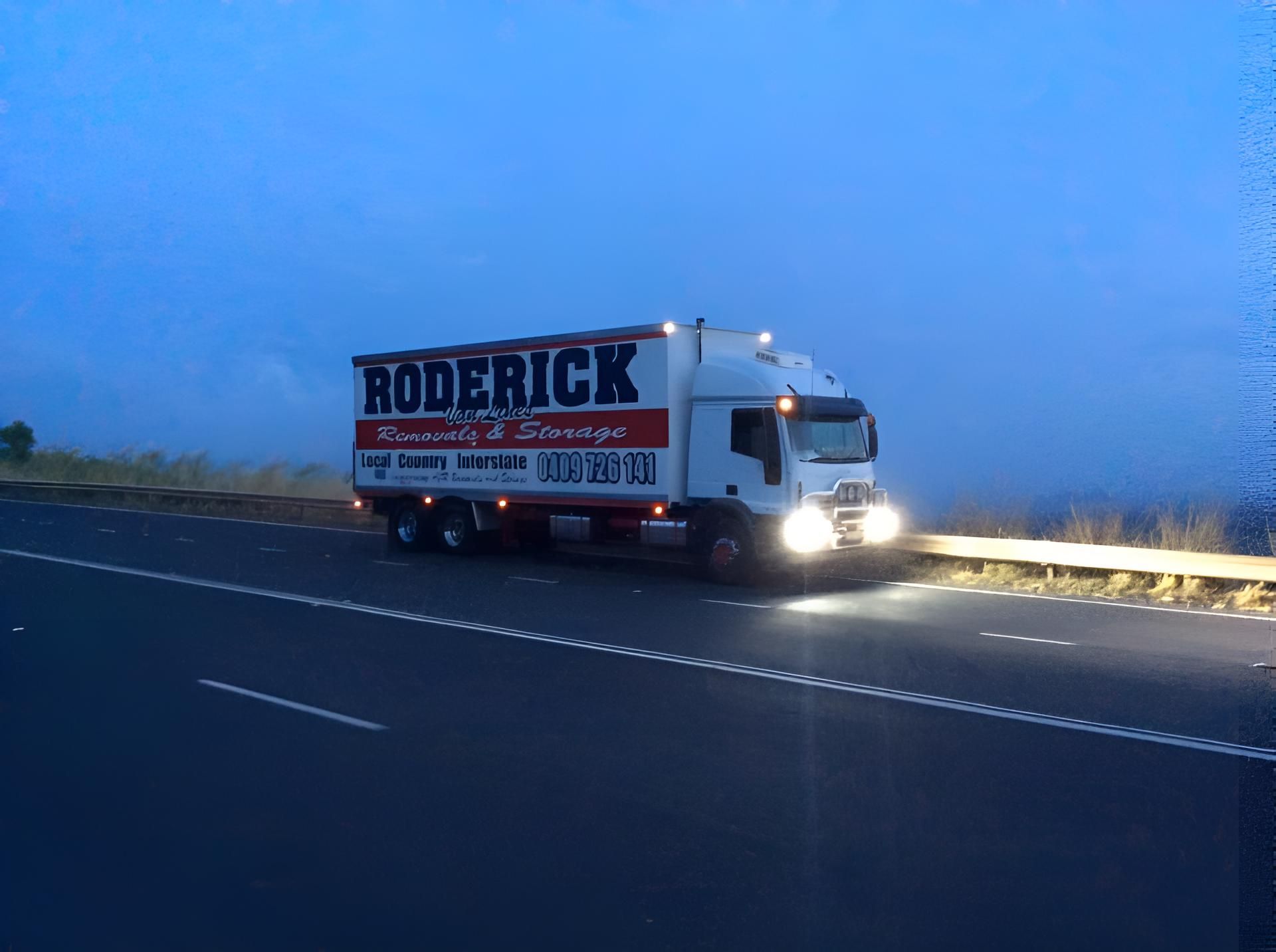 A Boderick Truck is Driving Down a Highway at Night — Roderick Removals & Van Lines In Gladstone Central, QLD