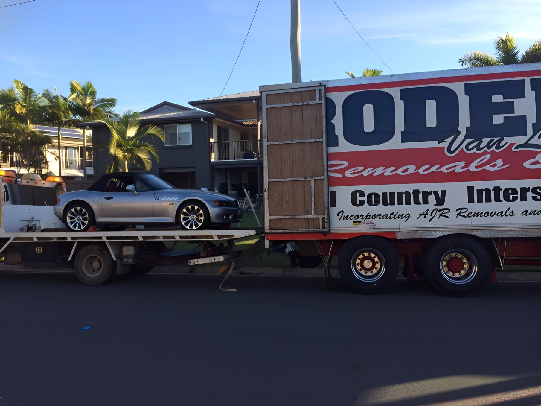 A Silver Car is Being Towed by a Rodei Truck — Roderick Removals & Van Lines In Gladstone Central, QLD