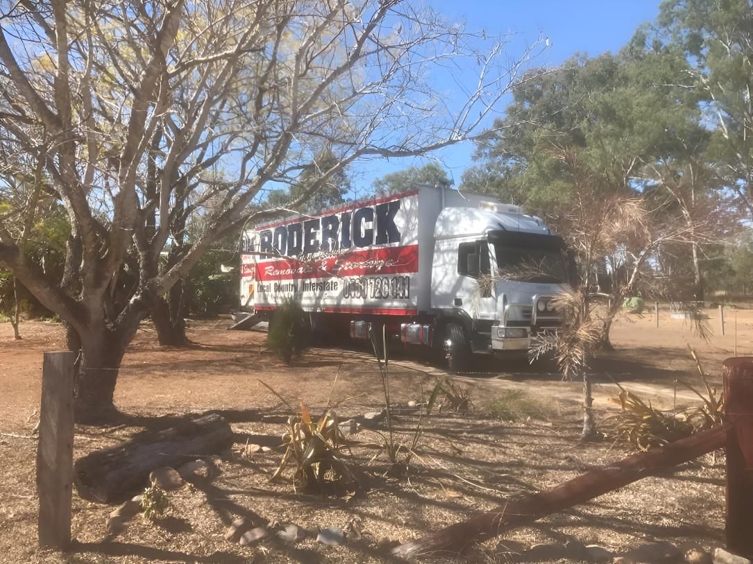 A White Truck is Parked in a Field Next to a Tree — Roderick Removals & Van Lines In Toowoomba, QLD