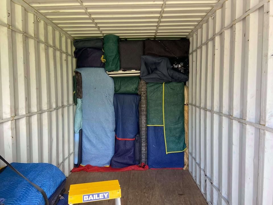 A Man is Standing in the Back of a Truck Filled With Boxes — Roderick Removals & Van Lines In Gladstone Central, QLD