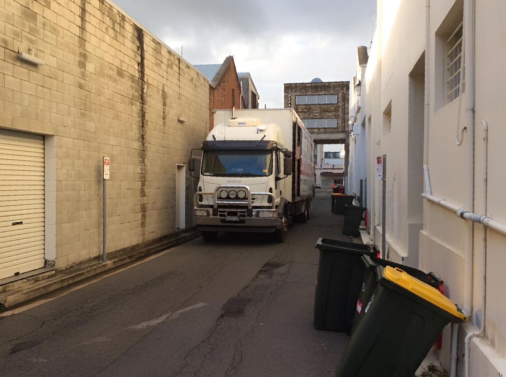 A white truck is parked in a narrow alleyway - Roderick Removals & Van Lines, Gladstone QLD