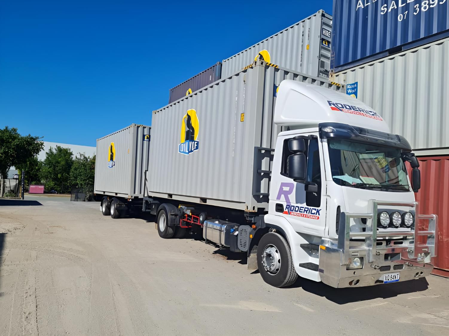 A Truck is Parked Next to a Row of Shipping Containers — Roderick Removals & Van Lines In Gladstone Central, QLD