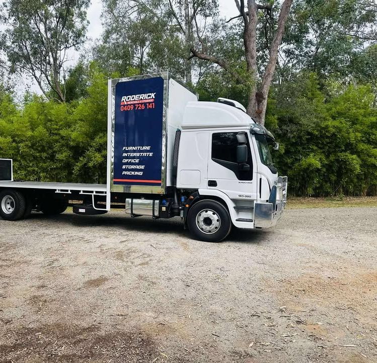 A White Truck is Parked in a Grassy Field — Roderick Removals & Van Lines In Mackay, QLD