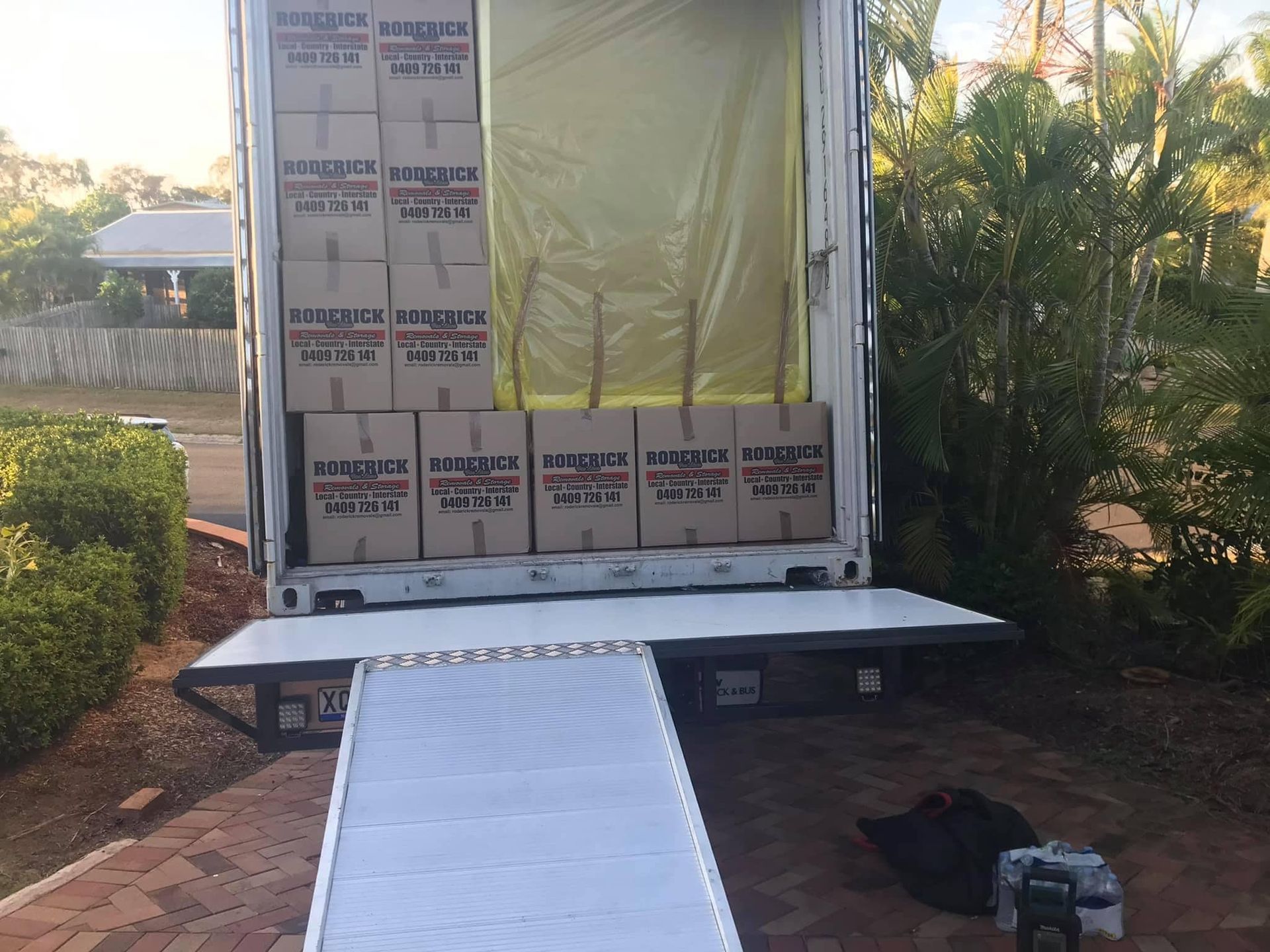 The back of a moving truck filled with boxes and a ramp — Roderick Removals & Van Lines In Gladstone Central, QLD