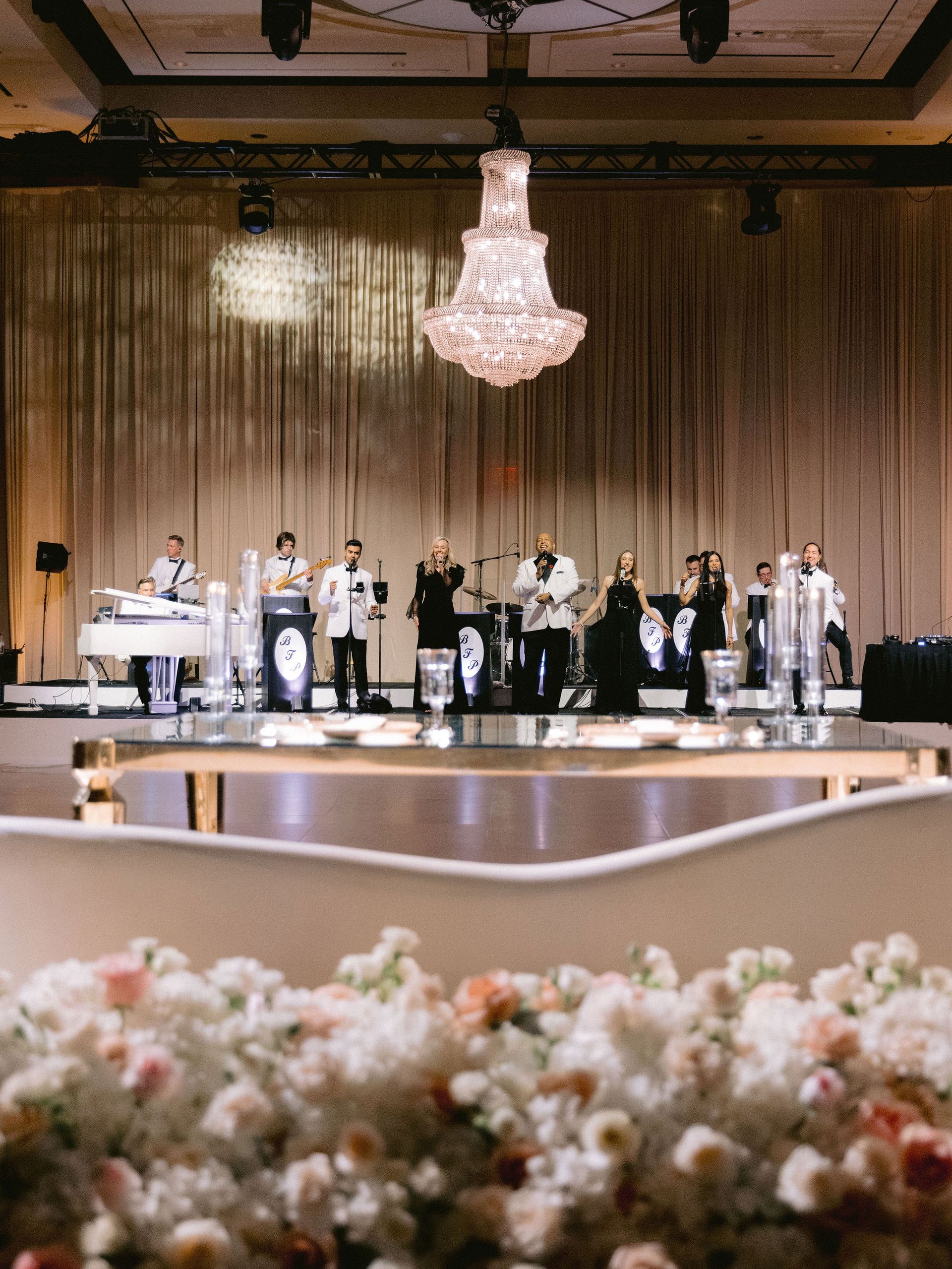 A band is playing in a large room with a chandelier hanging from the ceiling.