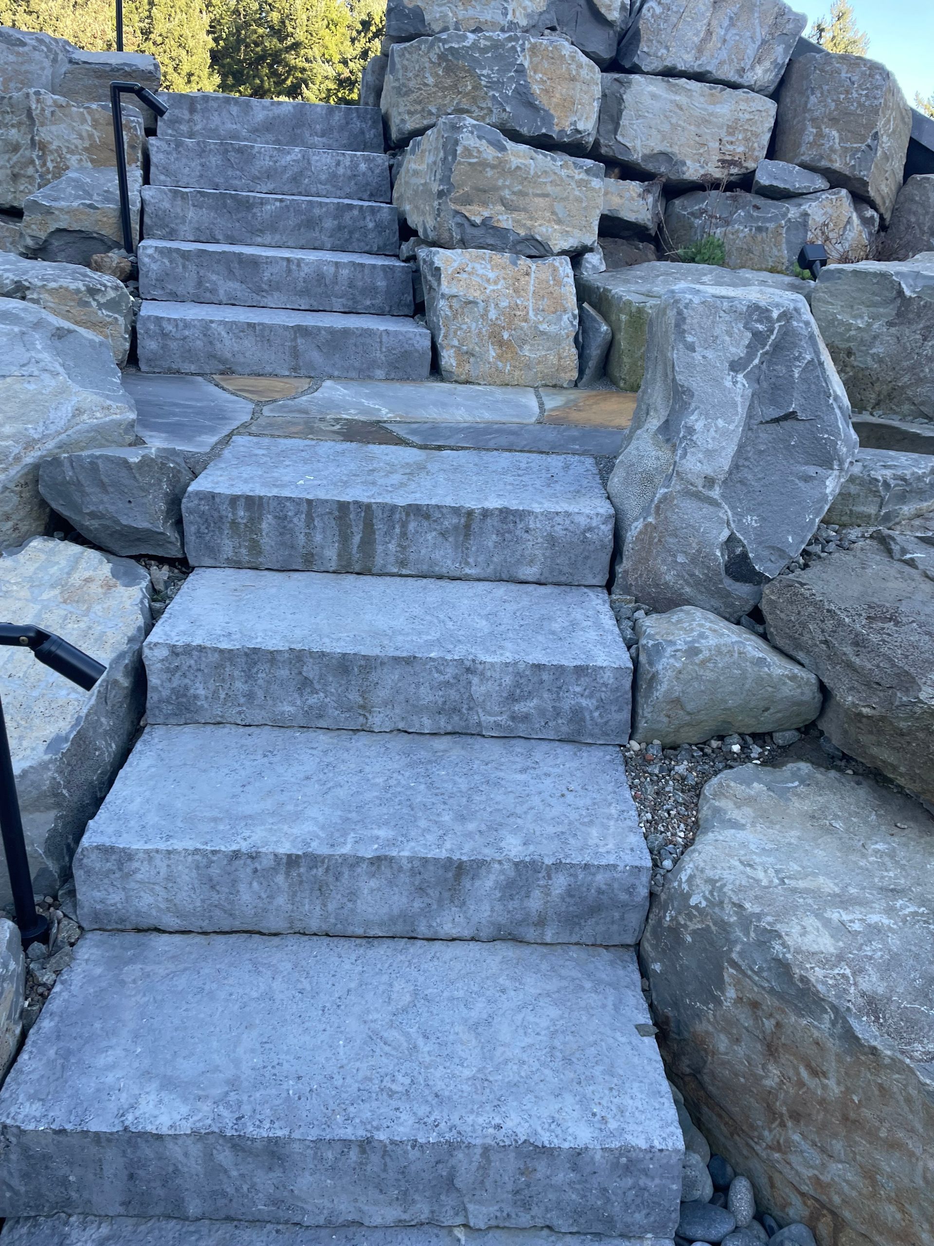 Stone steps built into a rocky hillside with a block wall on the right side.