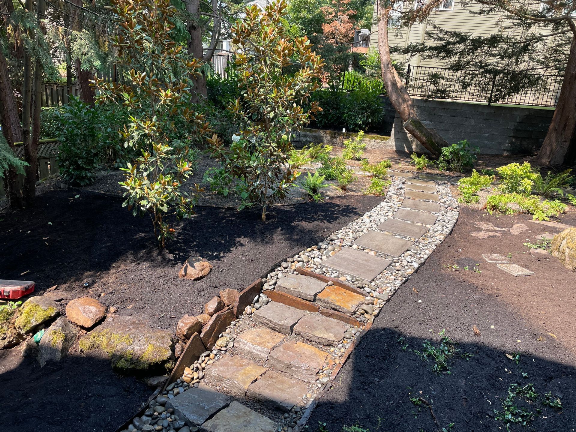 Garden path with brick and stone pavers curving through a shaded landscaped area
