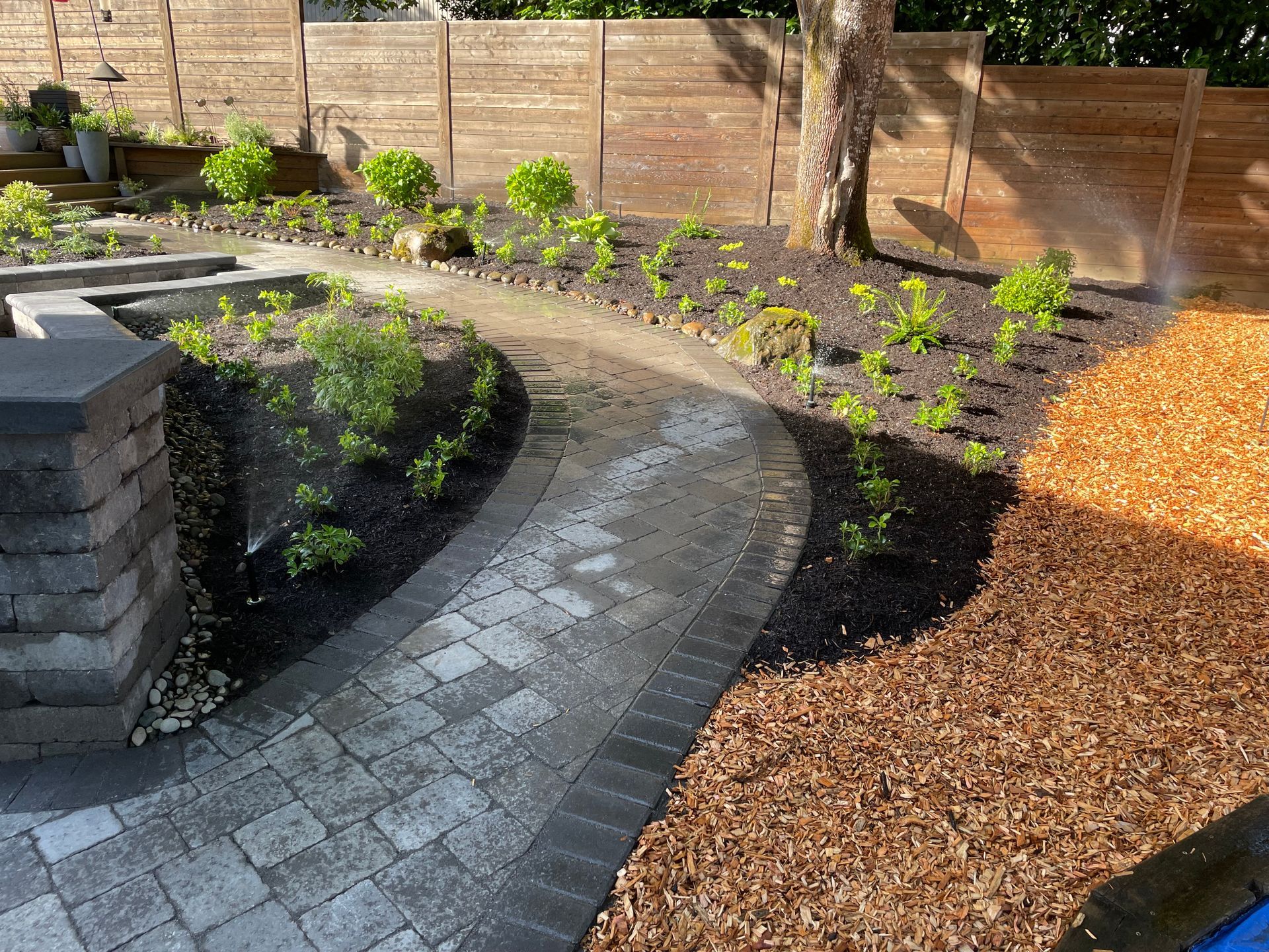 Curved stone garden path beside fresh plants and mulch in a landscaped yard