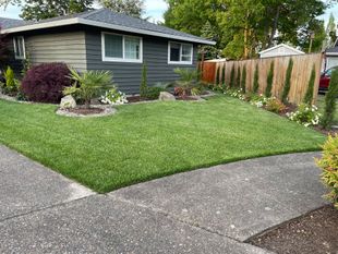 Suburban house with a neatly landscaped lawn, curved driveway, and wooden fence