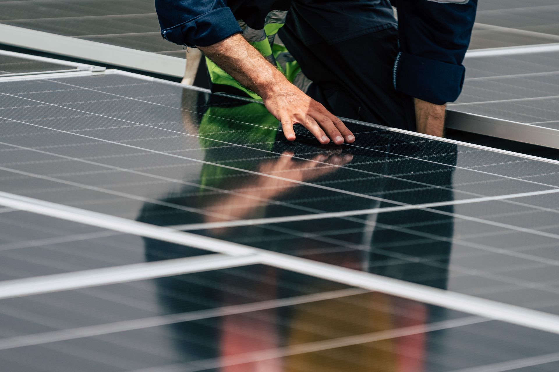 Person in work clothes installing solar panels on a rooftop.