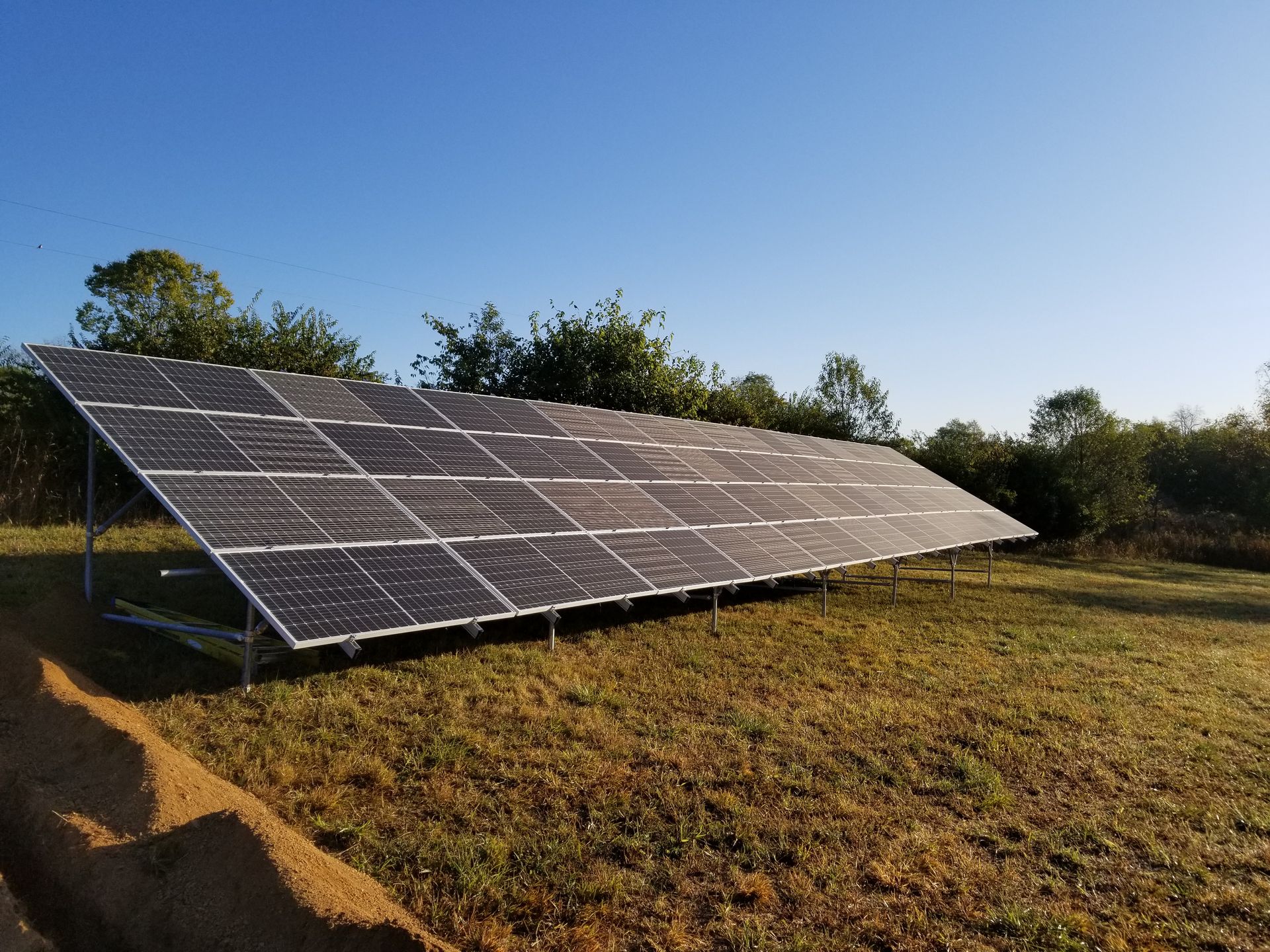 Solar panels in a field under a clear blue sky.