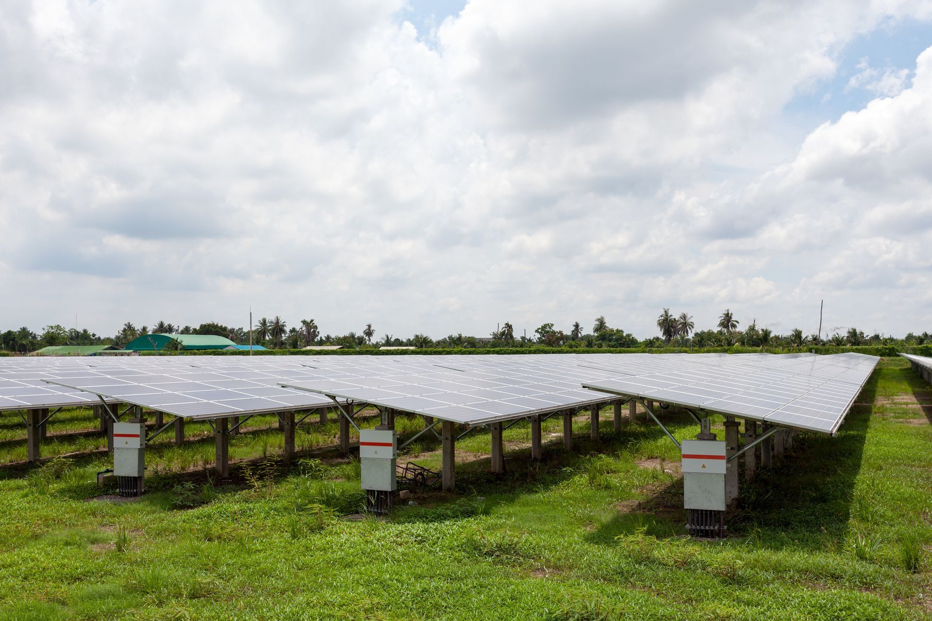 Solar panels in a grassy field under a cloudy sky, generating renewable energy.