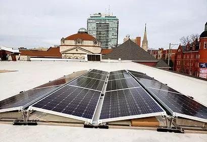 Solar panels installed on a flat rooftop in an urban cityscape.