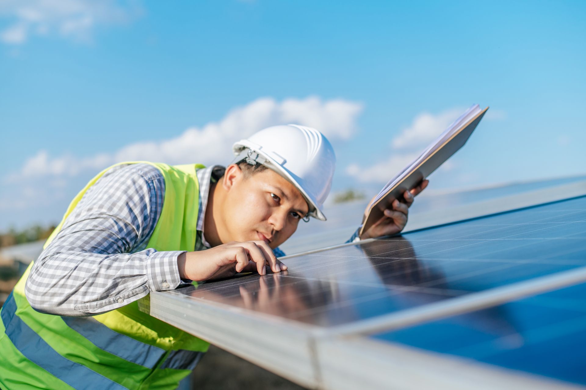 Technician inspecting solar panels on a rooftop under a blue sky