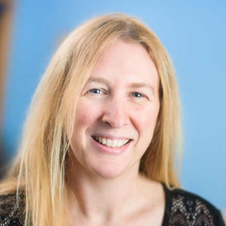 Smiling woman with long blonde hair against a blue background