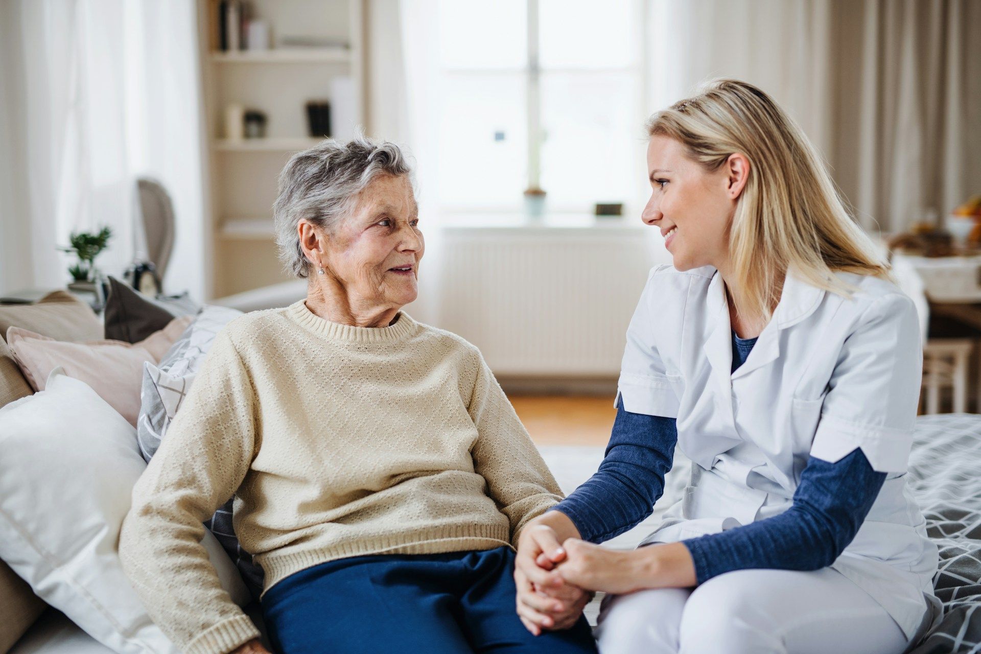 Nurse talking with a seated patient in a bright living room