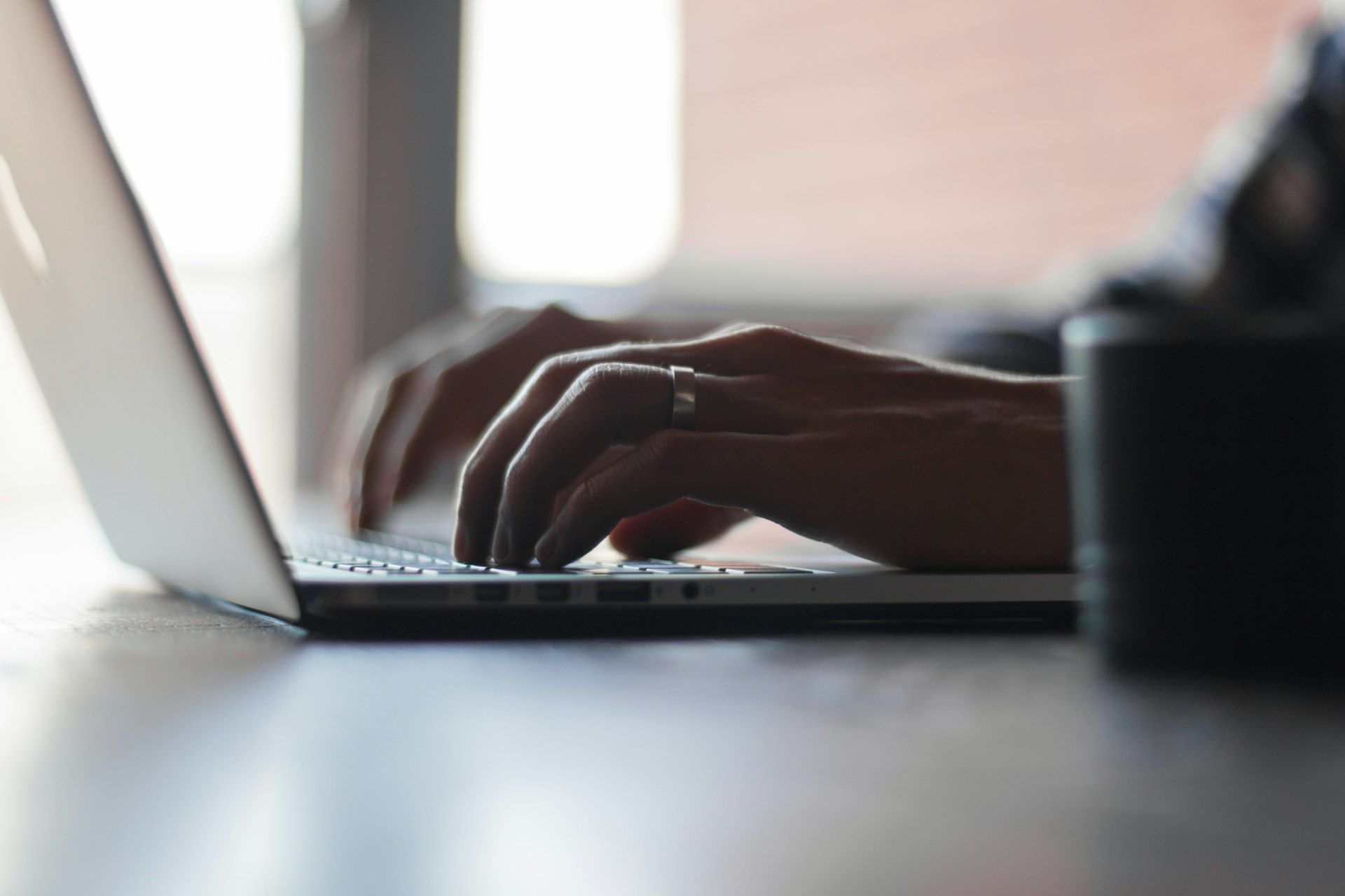 Hands typing on a laptop in a softly lit workspace