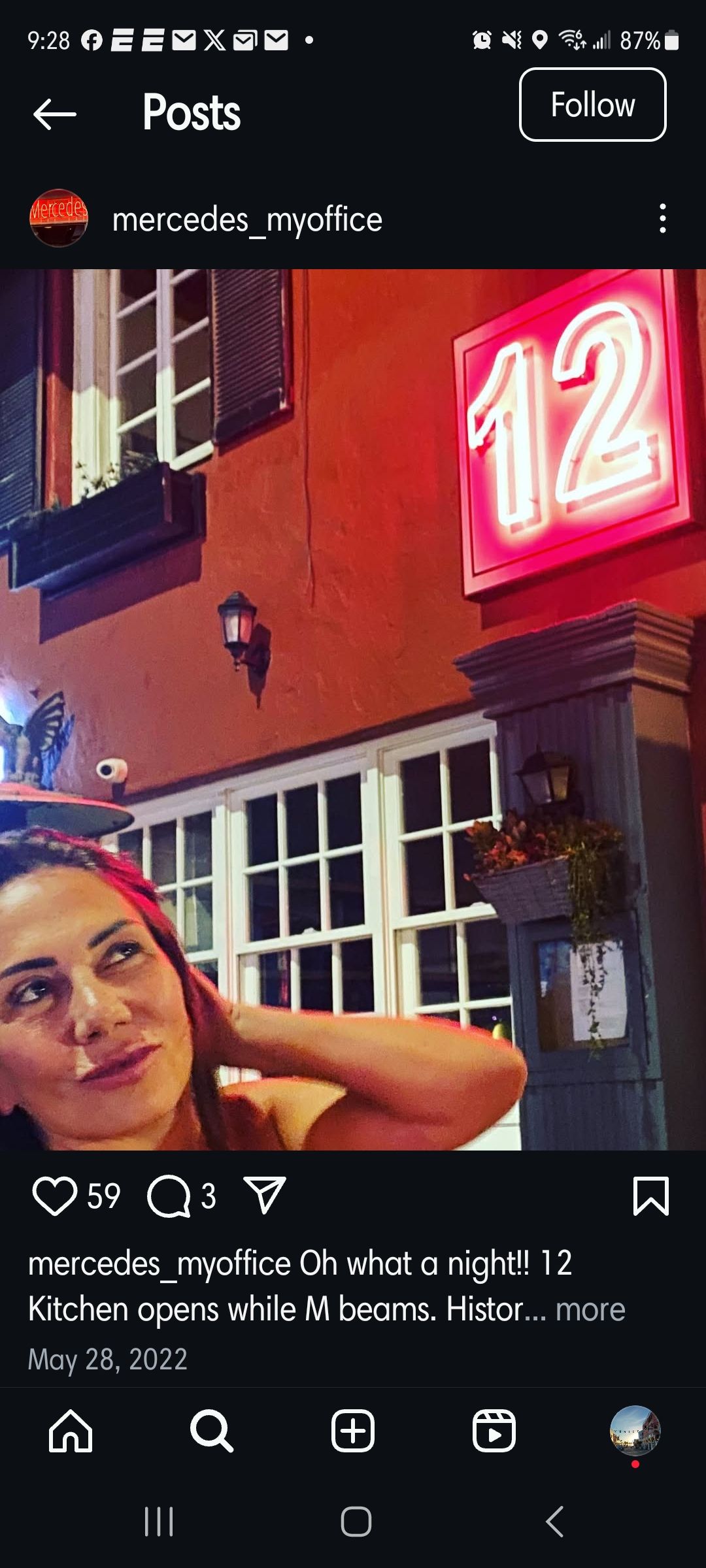 A woman is standing in front of a neon sign that says 12