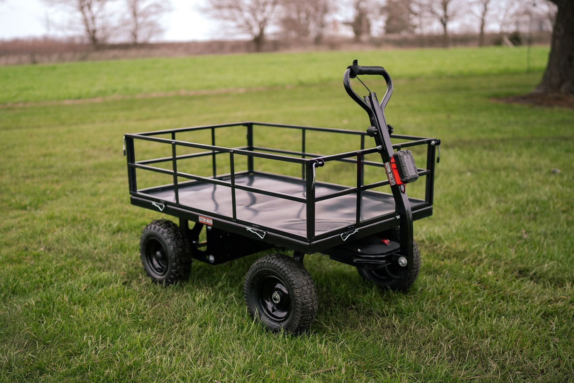 Black four-wheeled utility cart with railings and a handle on a white background