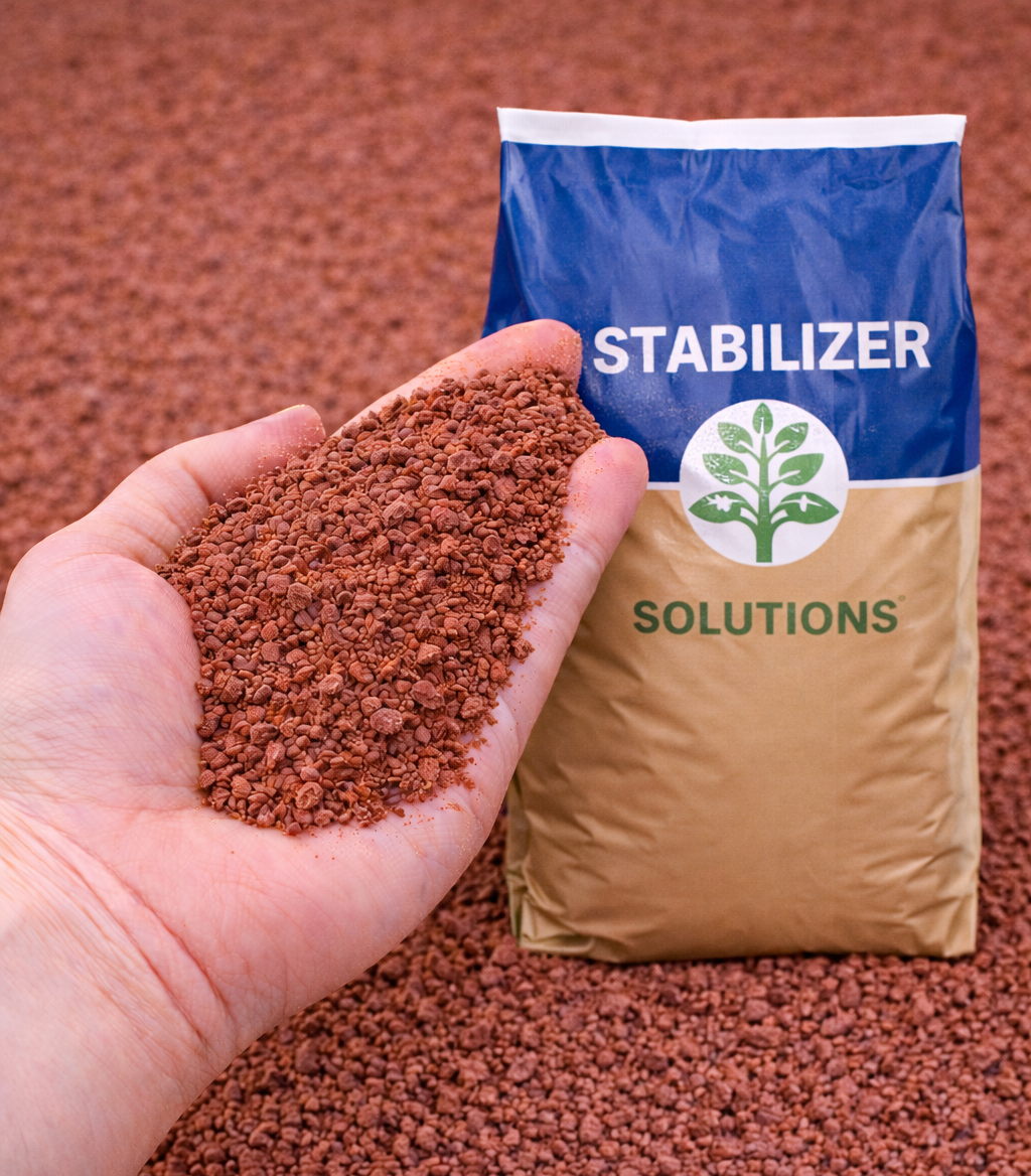 Hand holding brown granules beside a bag labeled “STABILIZER SOLUTIONS” on a reddish surface