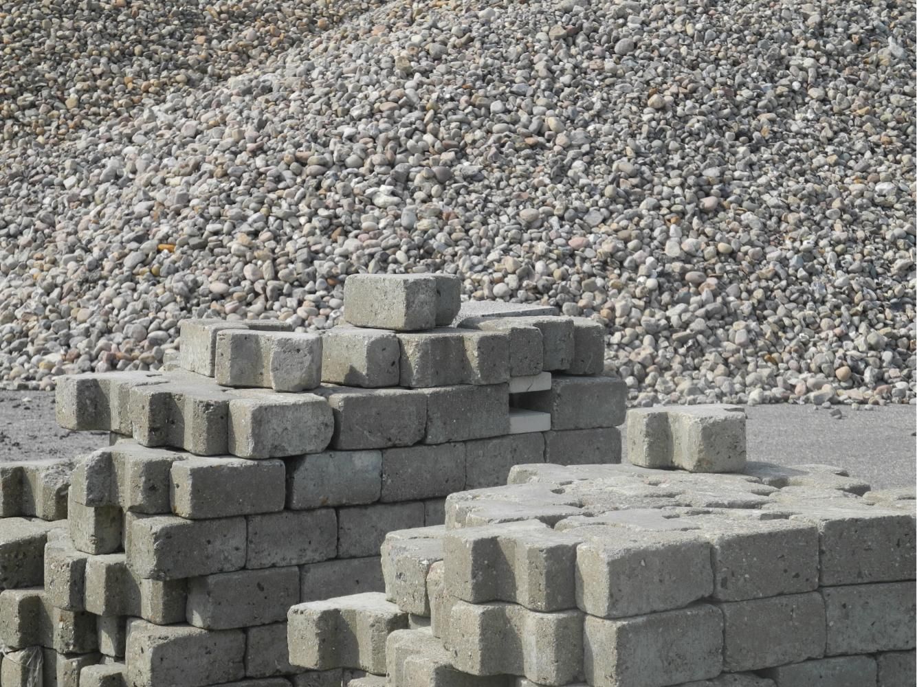 Stacks of gray concrete blocks in front of a gravel pile at a construction site