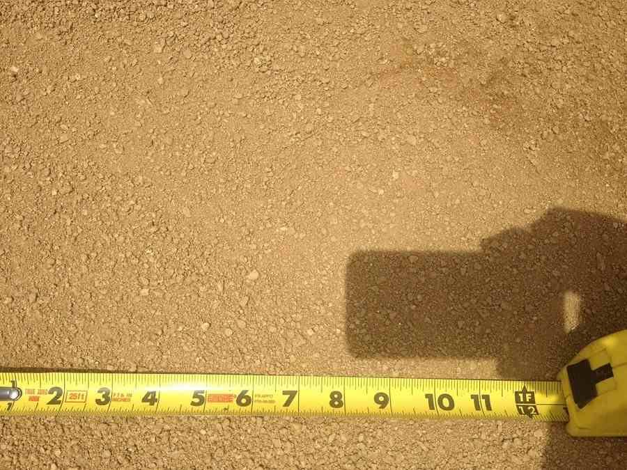 Yellow measuring tape along tan ground with a dark shadow at the right edge.