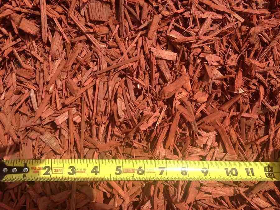 Red mulch ground cover with a yellow measuring tape laid along the bottom edge.