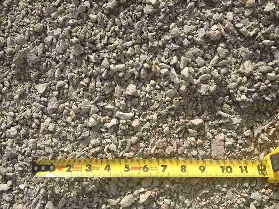 Yellow tape measure on gravel ground, showing inches near 2 to 11.