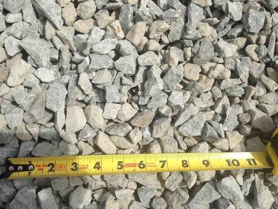 Measuring tape laid across a bed of gray crushed gravel stones