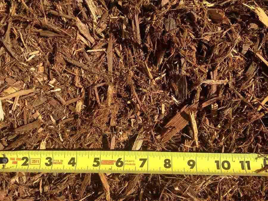Brown mulch or wood chips with a yellow measuring tape along the bottom edge.